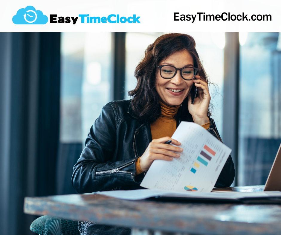 woman at work reviewing reports with a smile on her face talking on a cell phone